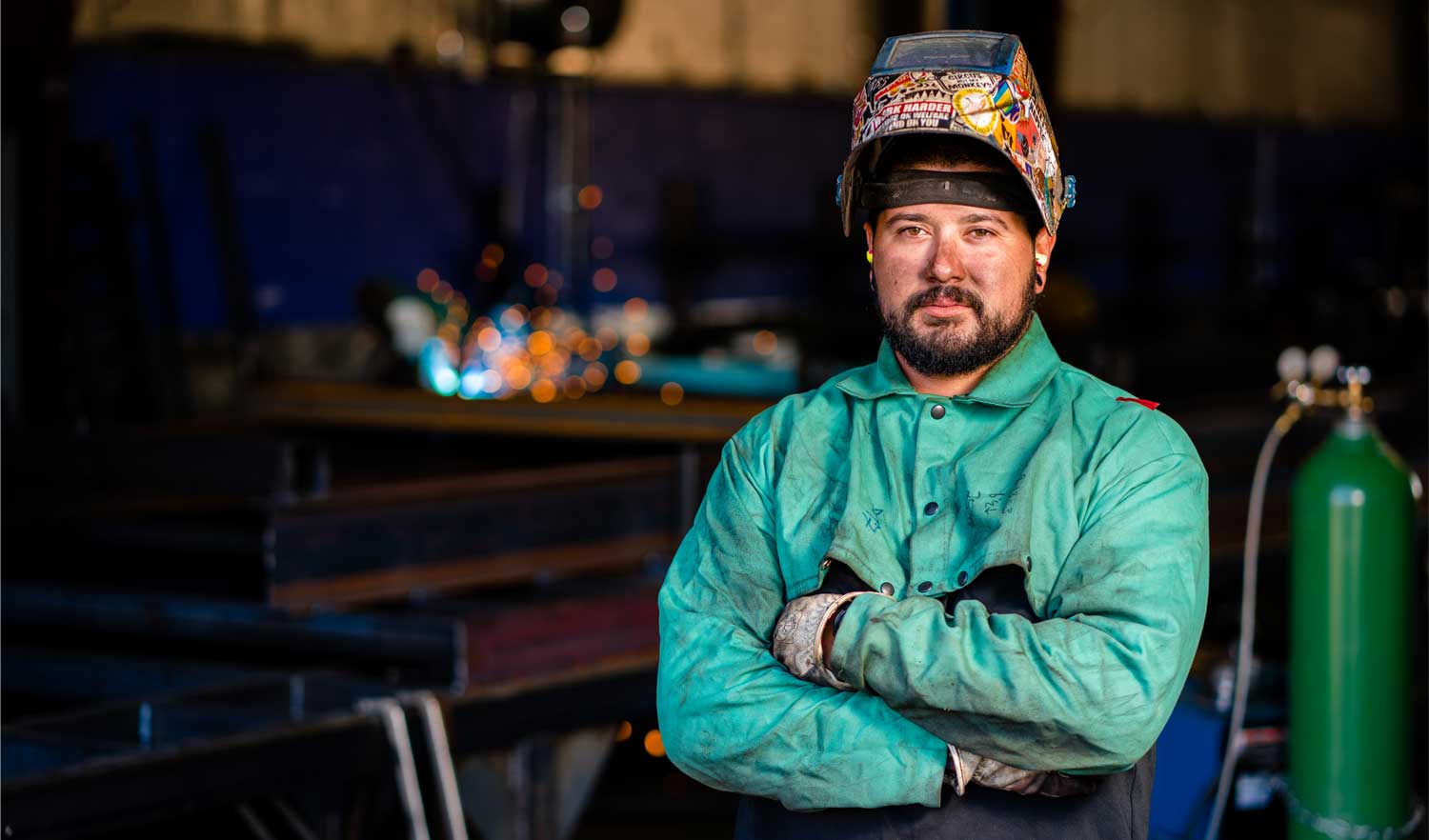 welder with visor up and arms crossed looking at camera