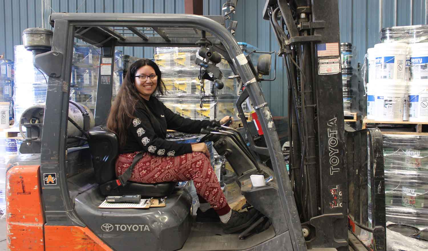 smiling female forklift driver in warehouse